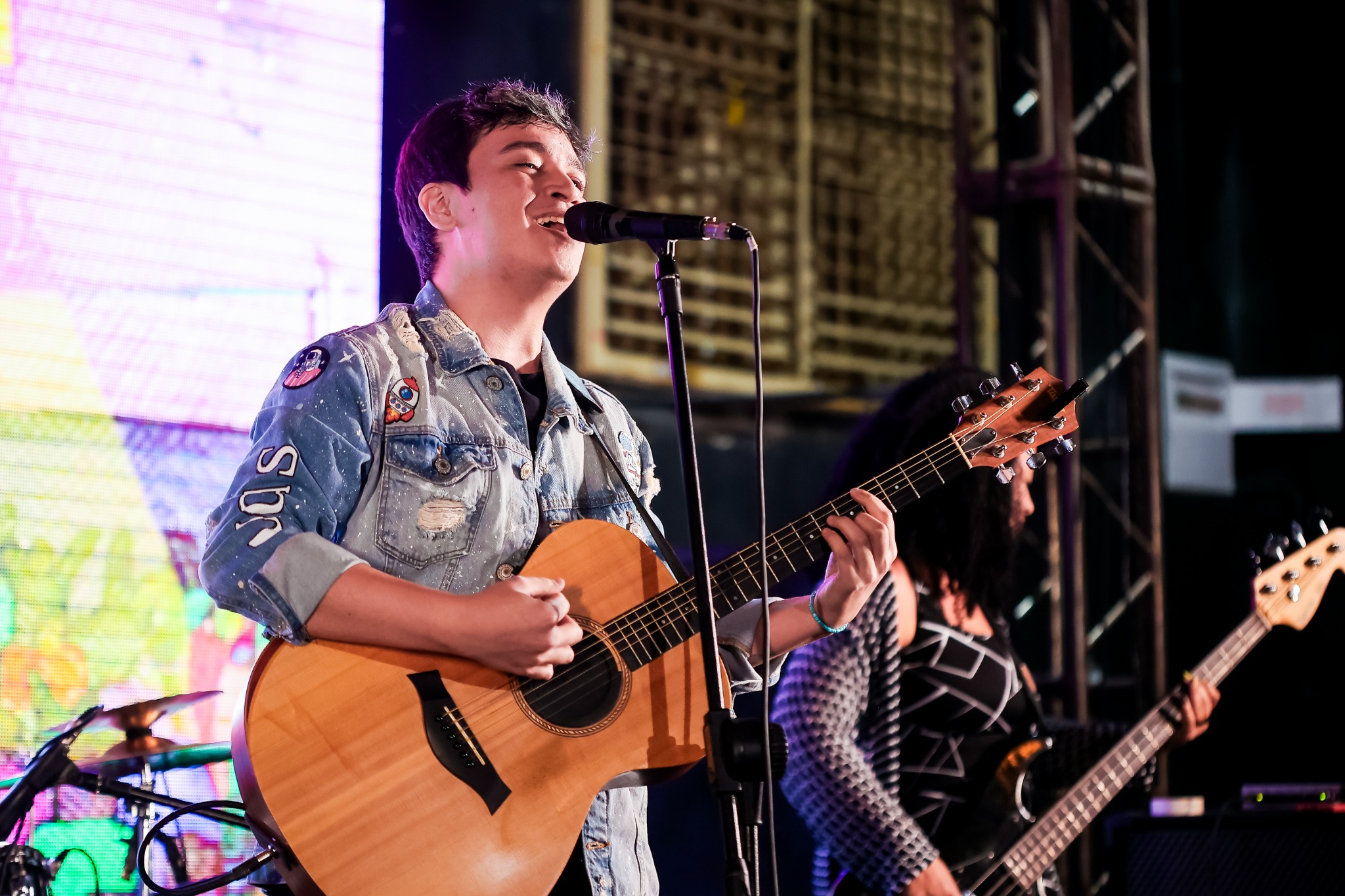 TENGUAM cantando e tocando violão durante uma apresentação ao vivo